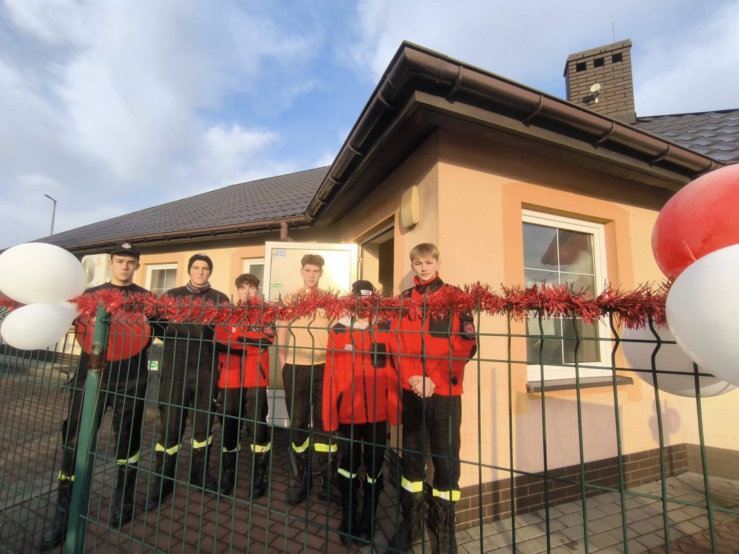 Strażacy ochotnicy przed budynkiem 