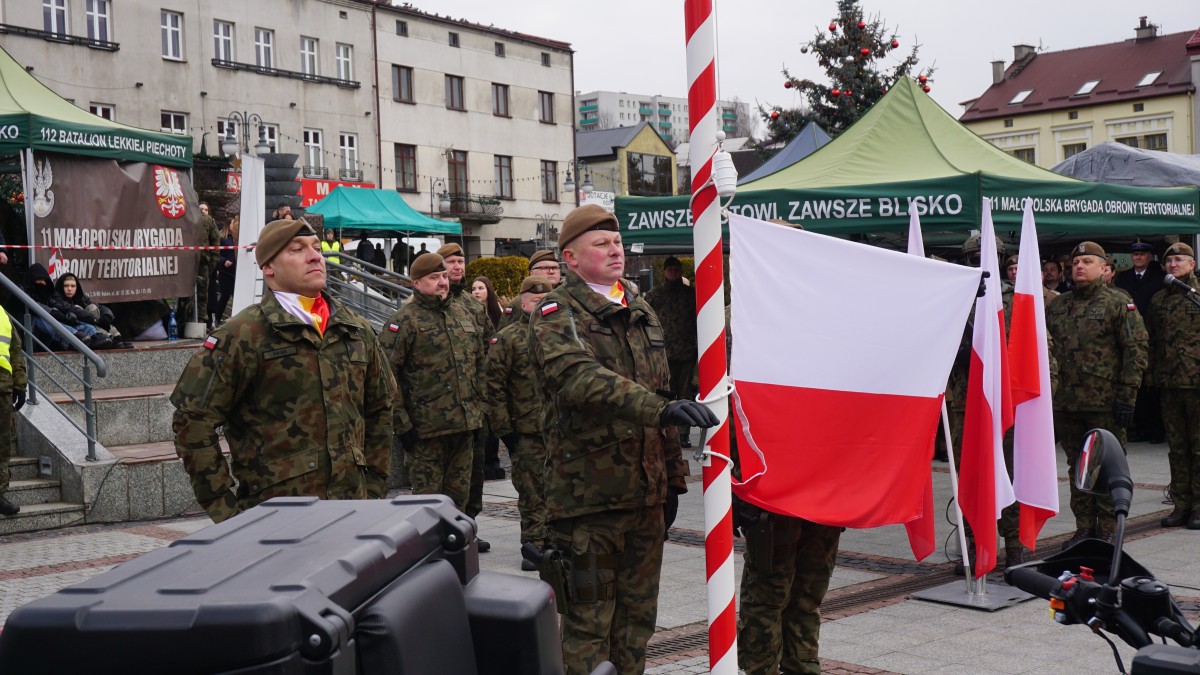 Zdjęcie żołnierzy, którzy wciagają na masz polską flagę.