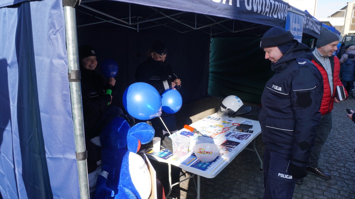 Zdjęcie stoiska chrzanowskiej policji. Przy nim stoi 3 funkconariuszy. Przed nimi stolik z materiałami inforamcyjnymi.