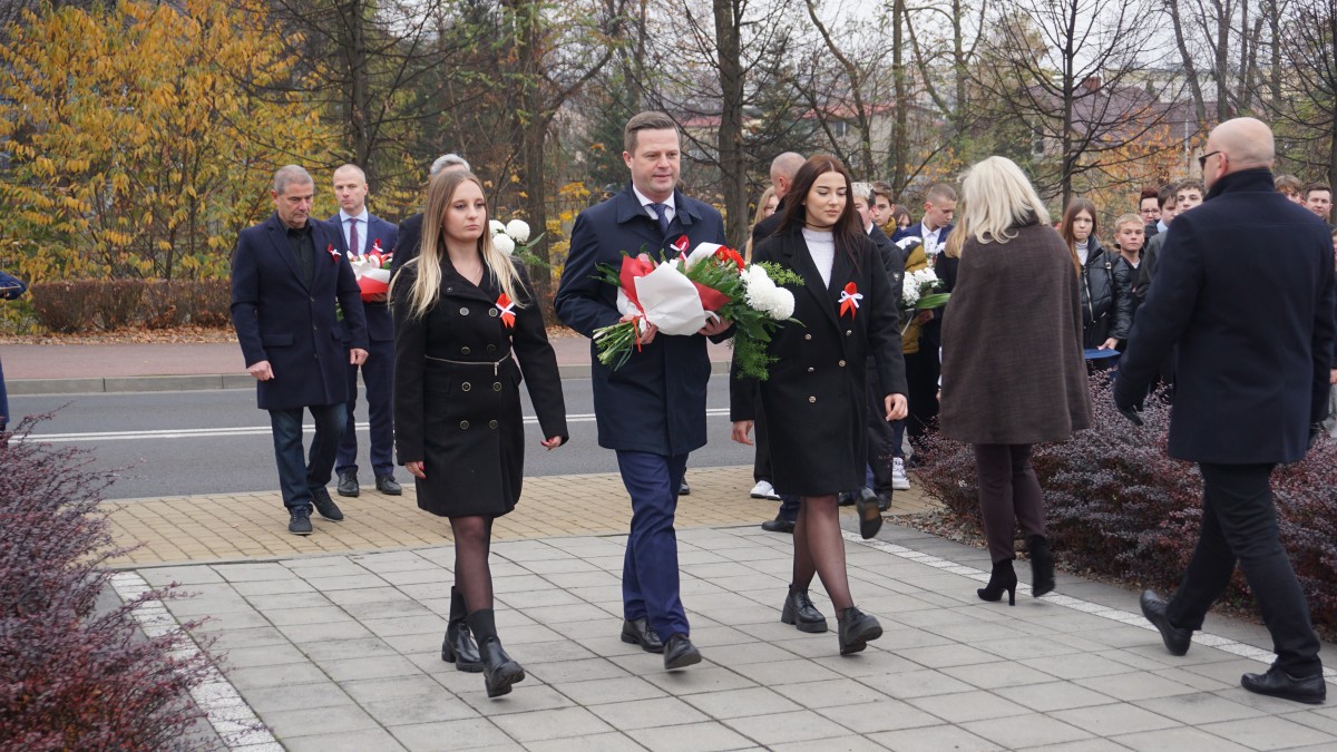 Starosta z kwiatami biało-czerwonymi maszeruje z dwoma uczennicami pod pomnik Piłsudskiego 