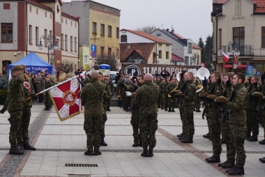 Zdjęcie, na pierwszym planie widać żołnierzy, którzy składają przysięgę na płycie rynku w Trzebini. W tle widac okierstrę i obseratorów. 